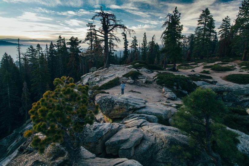 A hiker standing on granite above the clouds at sunset